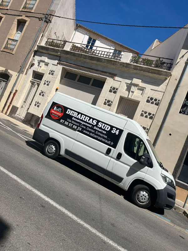 Camion de Débarras Hérault Sud 34 stationné dans une rue de village de l'Hérault