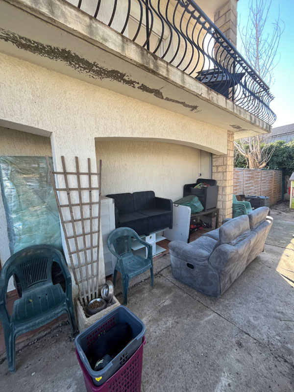 Canapé, salon de jardin et chaises en plastique à évacuer sur une terrasse dans l'Hérault