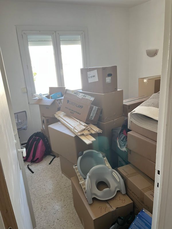 Pièce remplie de cartons et d'affaires avant enlèvement lors d'un débarras
