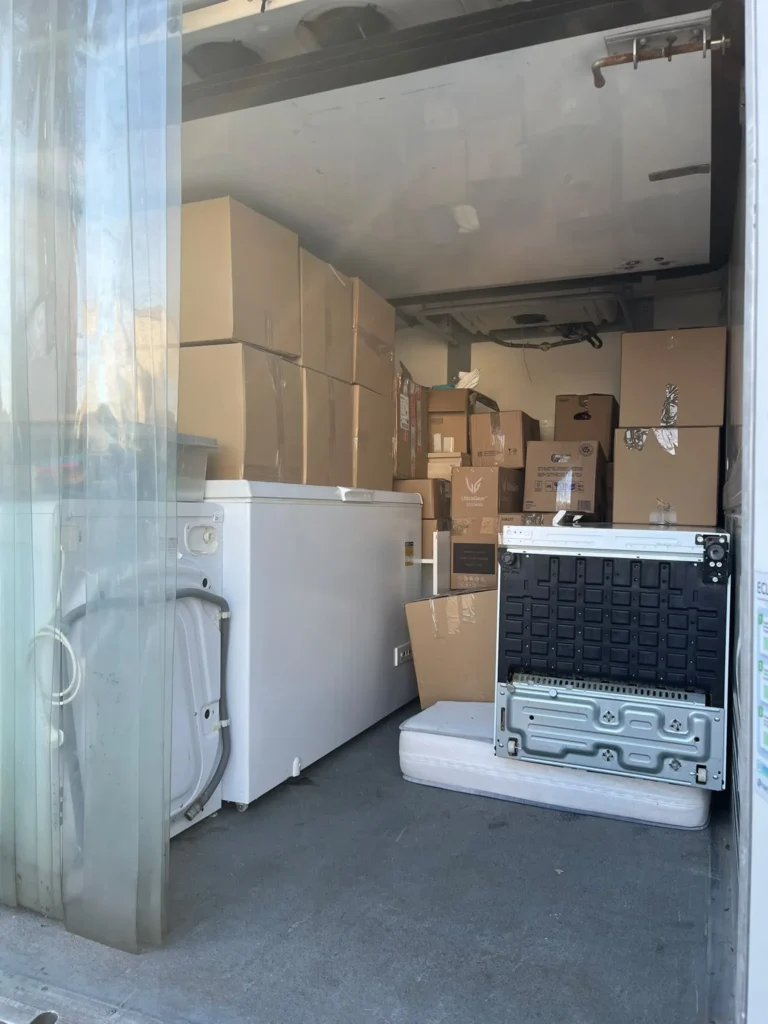 Cellier encombré de cartons, d'un congélateur et d'un lave-linge