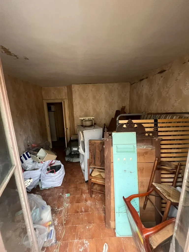 Pièce très encombrée de meubles et de sacs avant intervention