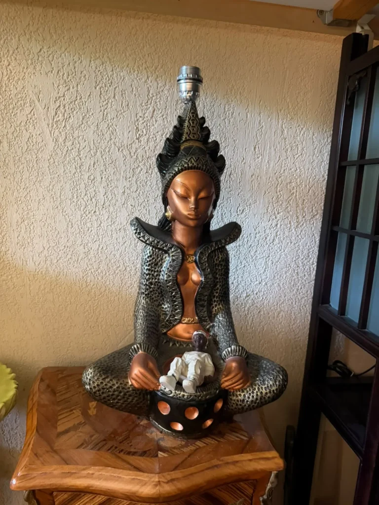 Lampe en forme de statue asiatique posée sur une table marquetée, récupérées lors d'un débarras